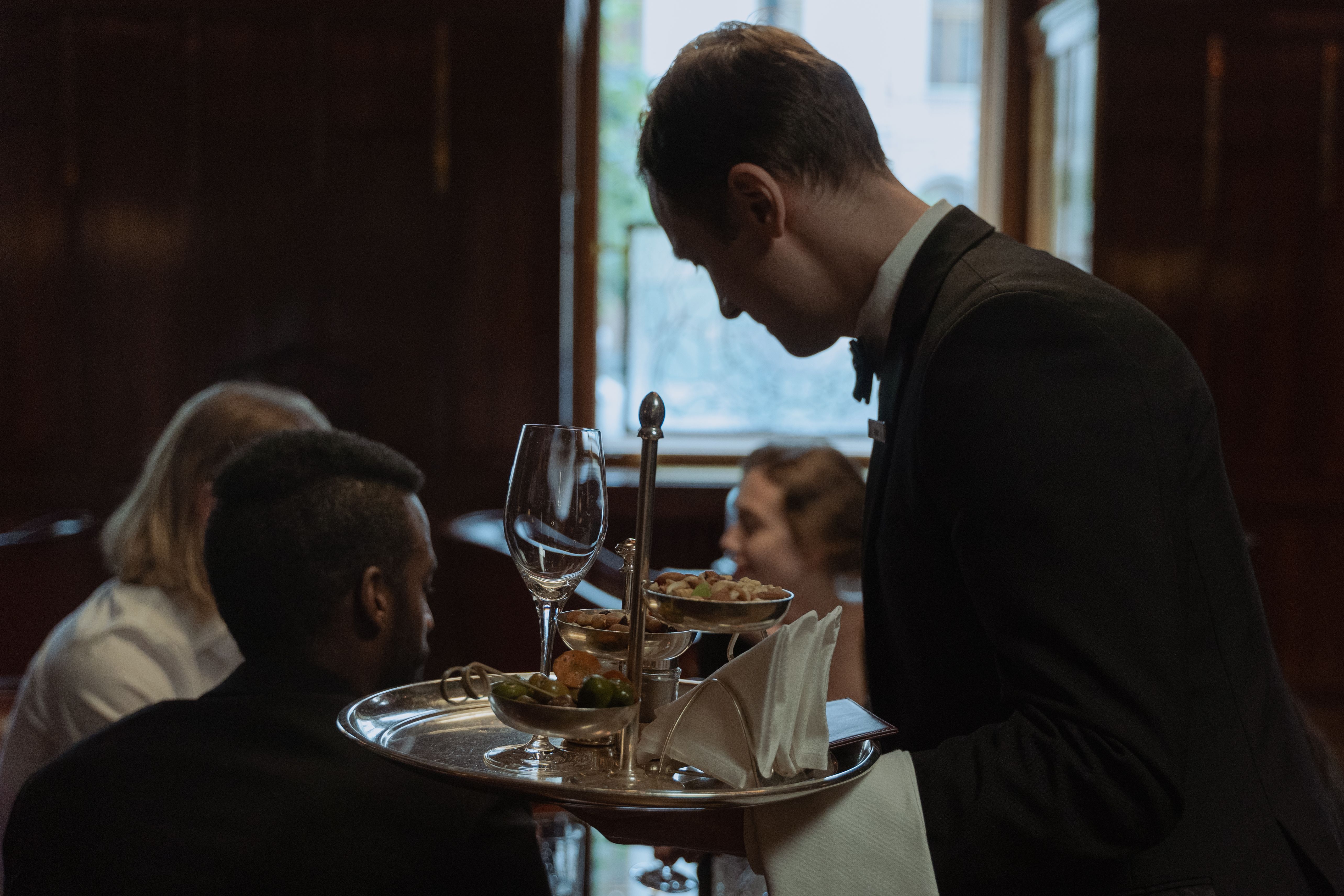 A fine dining waiter attentively serving a group of guests at an elegant restaurant table