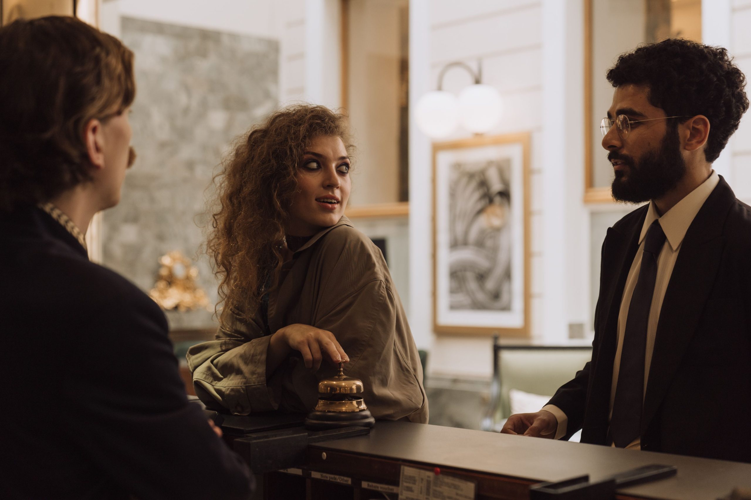 Hotel guests interacting with staff at a luxury reception desk, where staff read guests' needs before they ask