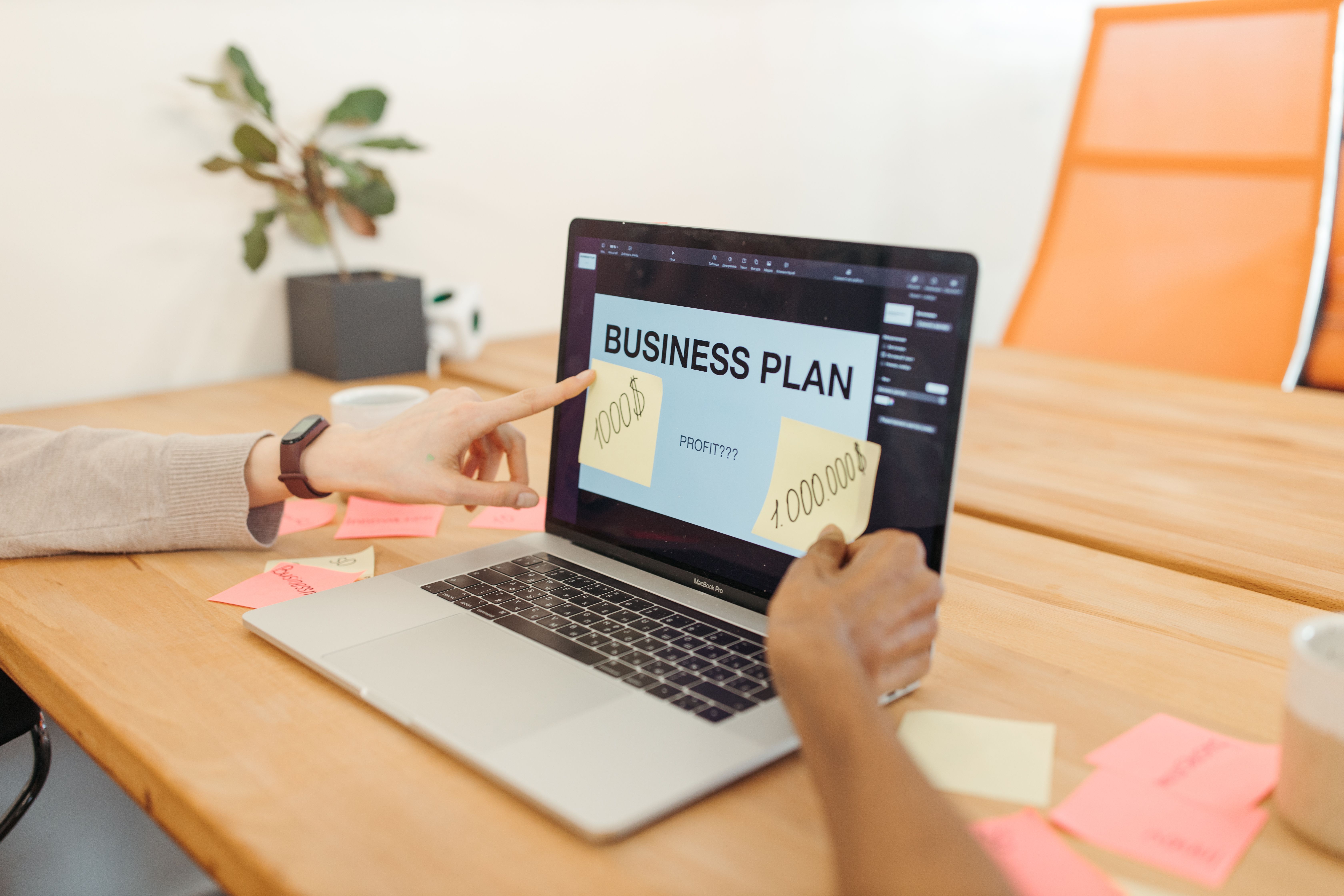 Hands collaborating on a business plan with a laptop in a modern office