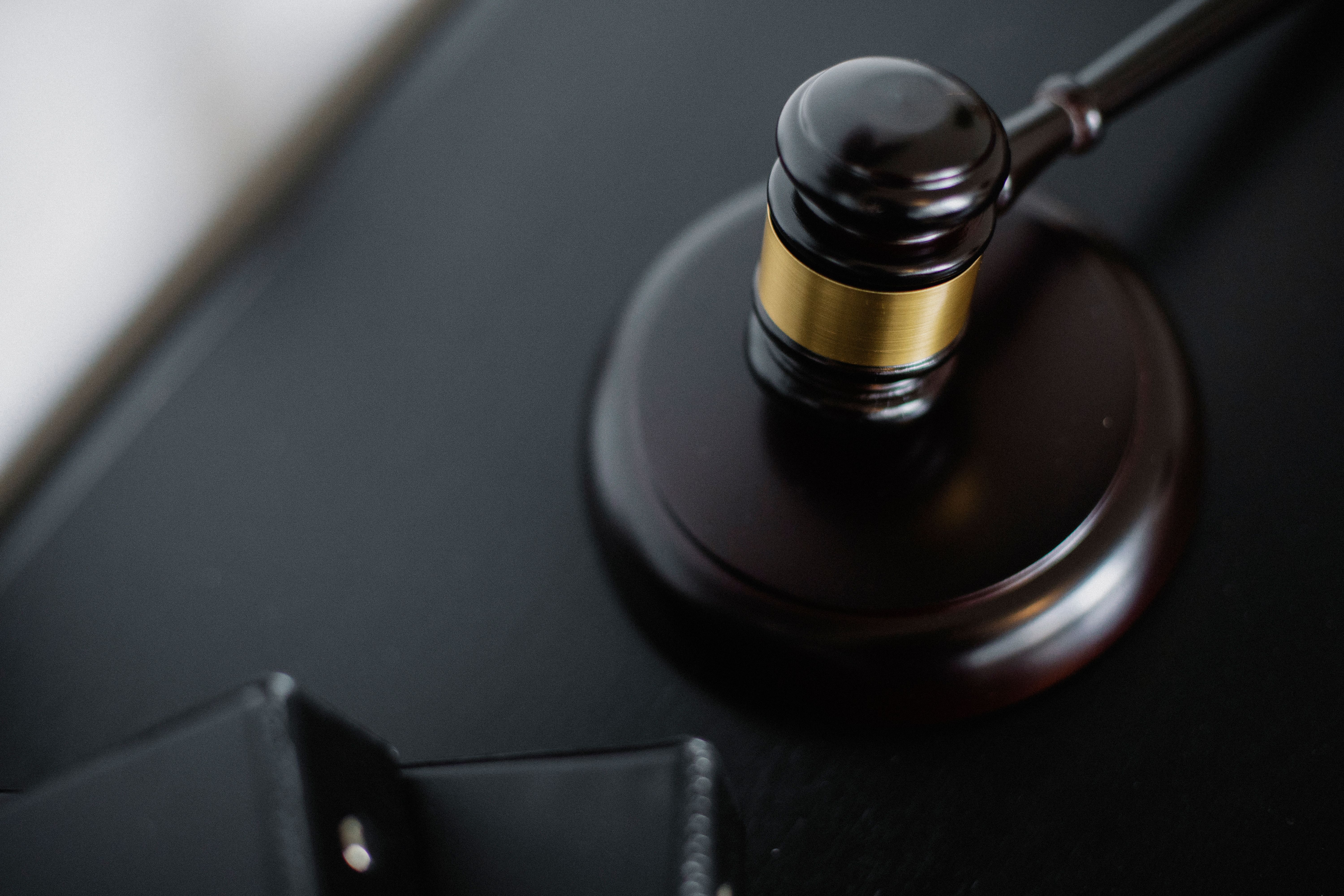 Wooden gavel and case folders on a courtroom table representing a major legal case