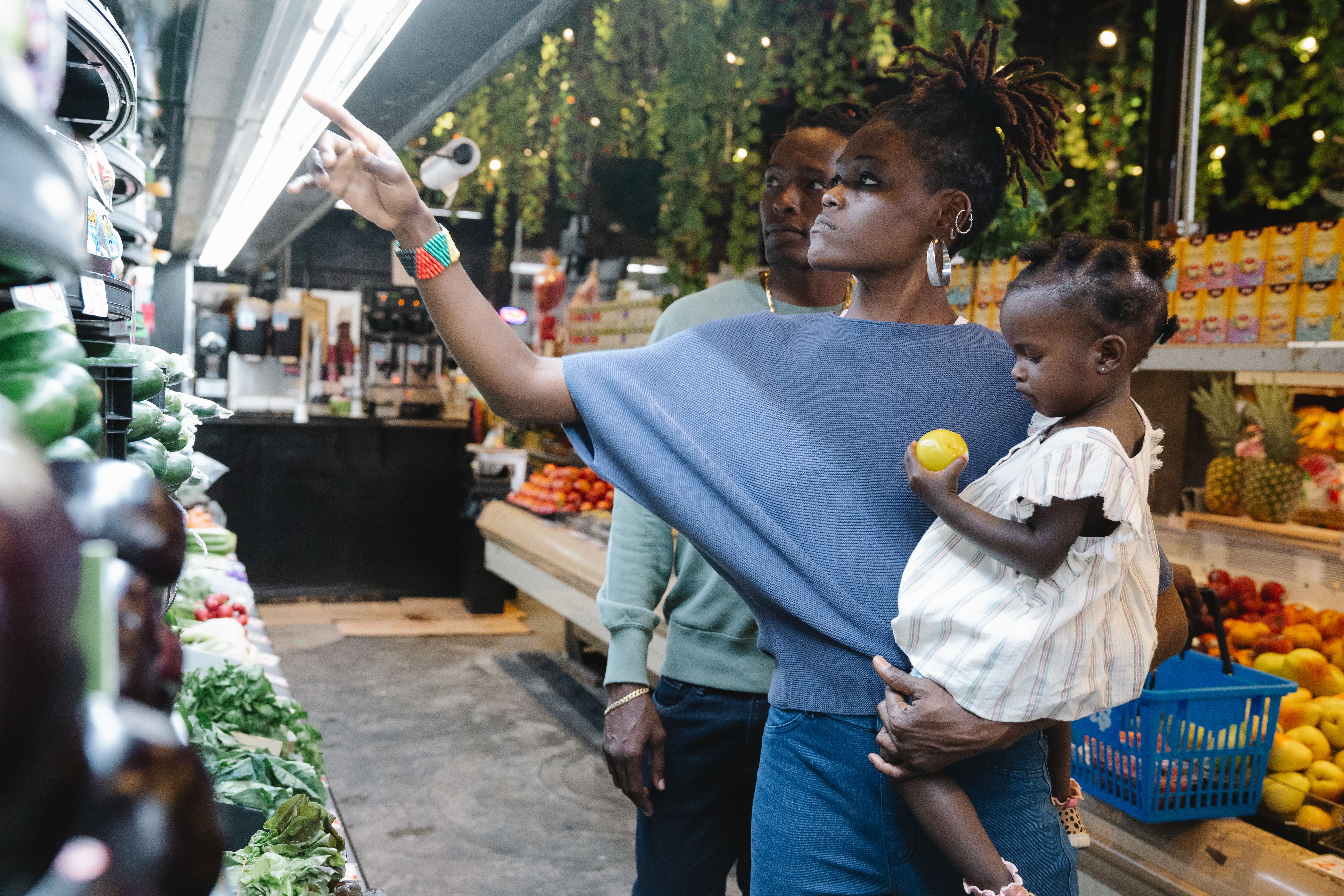 Family shopping for fresh produce in a supermarket, illustrating how transport costs affect household living expenses.
